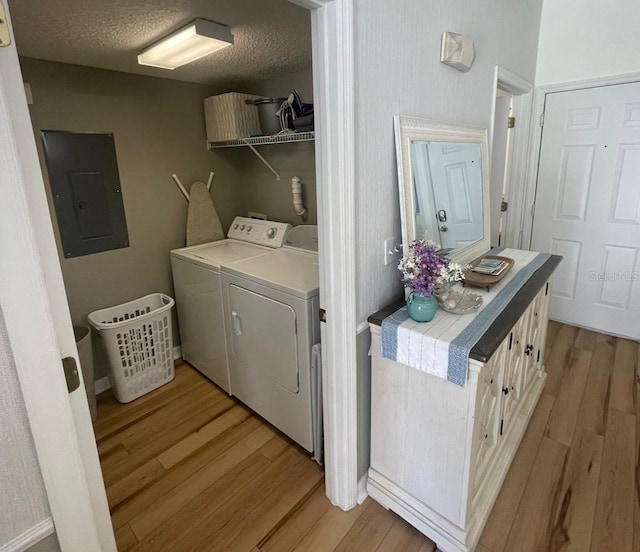 laundry room with washer and dryer, a textured ceiling, electric panel, and light hardwood / wood-style floors