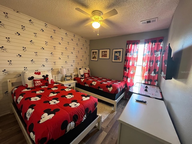 bedroom with a textured ceiling, ceiling fan, and dark wood-type flooring