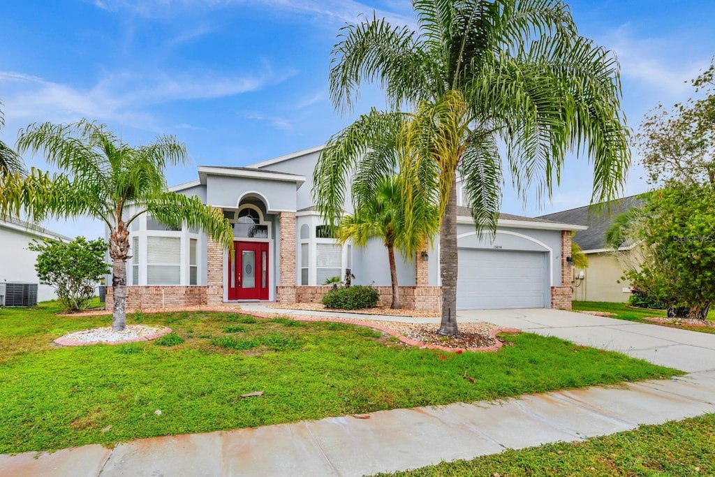 view of front of property with central AC, a front lawn, and a garage