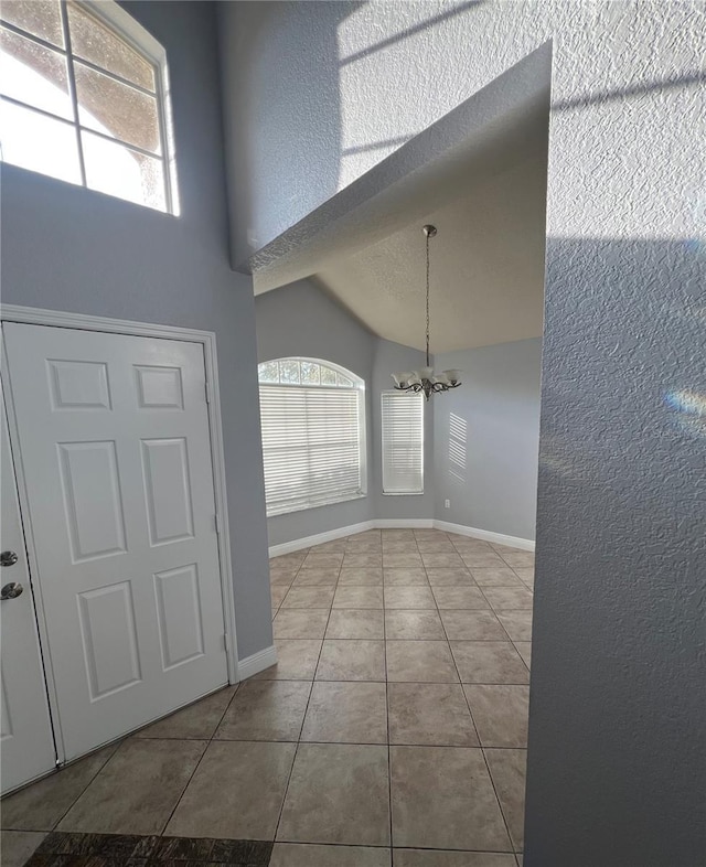 tiled foyer with a textured ceiling, a chandelier, and lofted ceiling