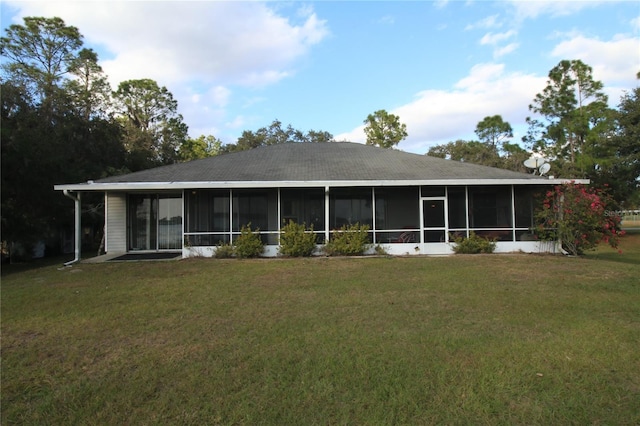 rear view of house with a yard and a sunroom