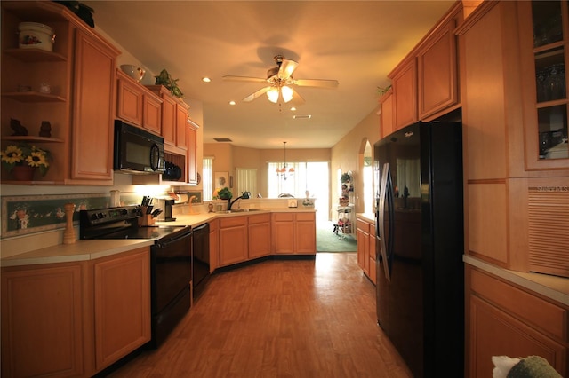 kitchen featuring decorative light fixtures, black appliances, sink, light wood-type flooring, and ceiling fan with notable chandelier