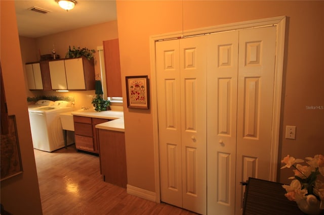 kitchen with washer and clothes dryer and light hardwood / wood-style flooring