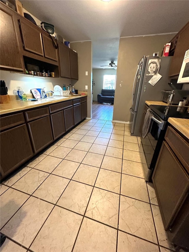 kitchen featuring electric range, light tile patterned floors, and dark brown cabinets