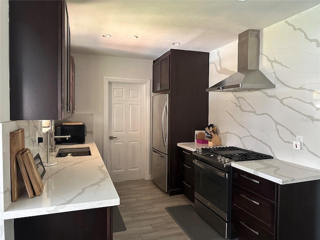 kitchen with wall chimney range hood, light hardwood / wood-style floors, tasteful backsplash, appliances with stainless steel finishes, and sink