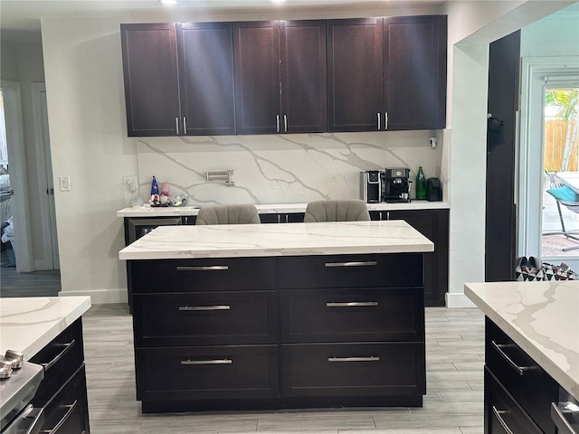 kitchen featuring tasteful backsplash, light stone countertops, and dark brown cabinetry