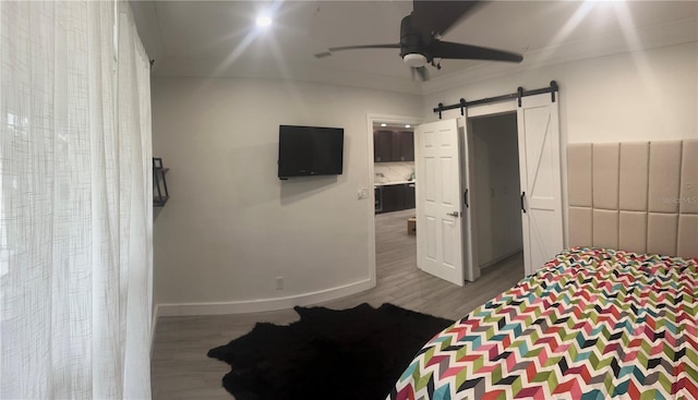 bedroom with ceiling fan, hardwood / wood-style flooring, and a barn door