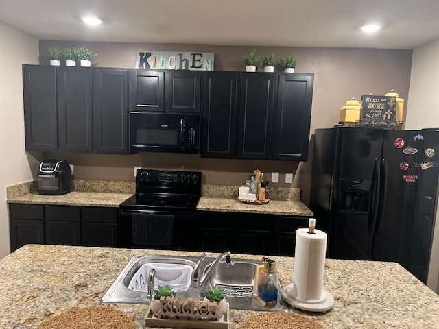 kitchen featuring black appliances, light stone counters, and sink