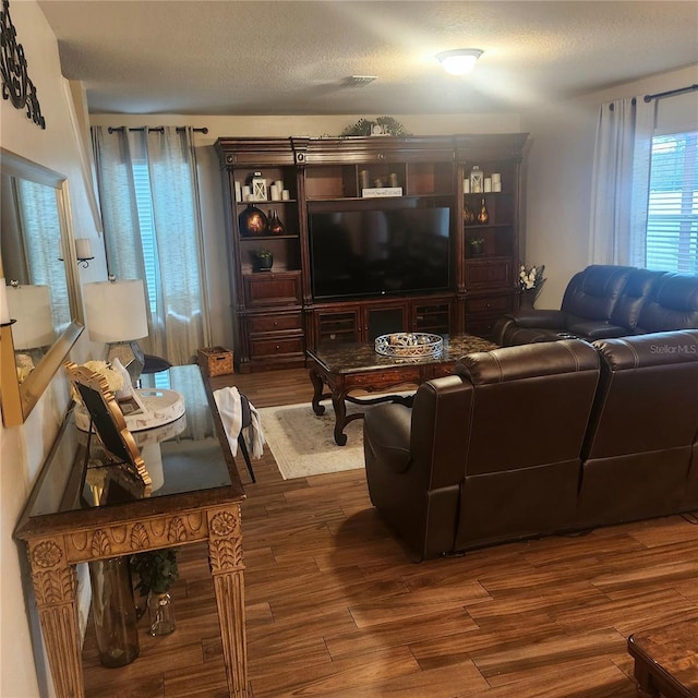 living room with a textured ceiling and dark hardwood / wood-style floors