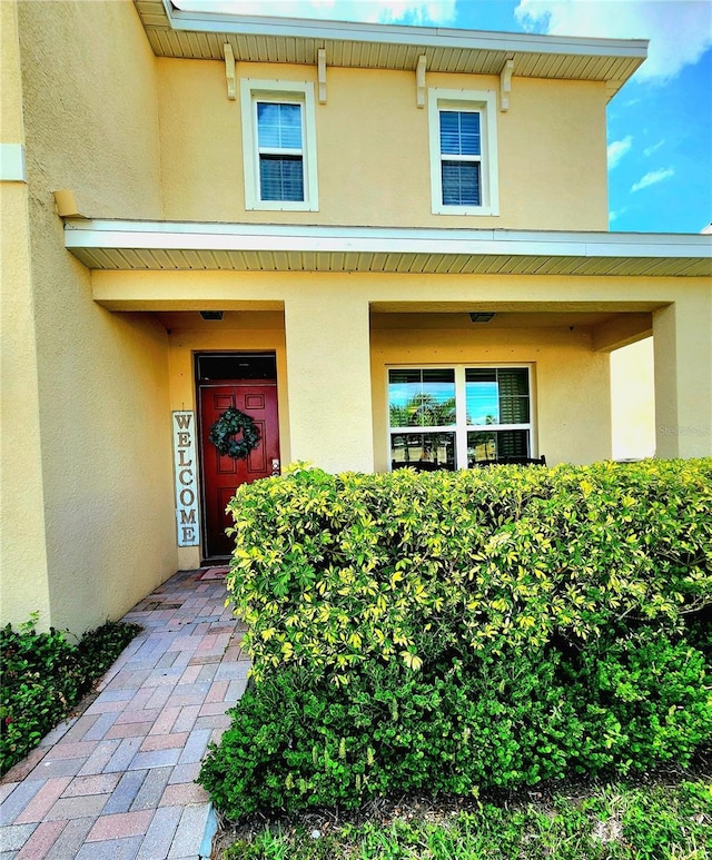 property entrance with a porch and stucco siding
