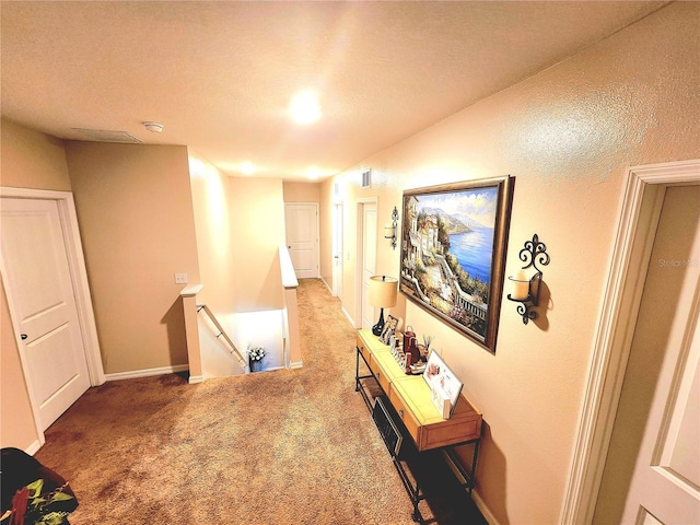 hallway with an upstairs landing, carpet, and visible vents