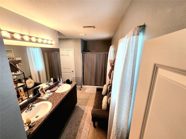 bathroom featuring visible vents, a textured ceiling, tile patterned flooring, and a sink