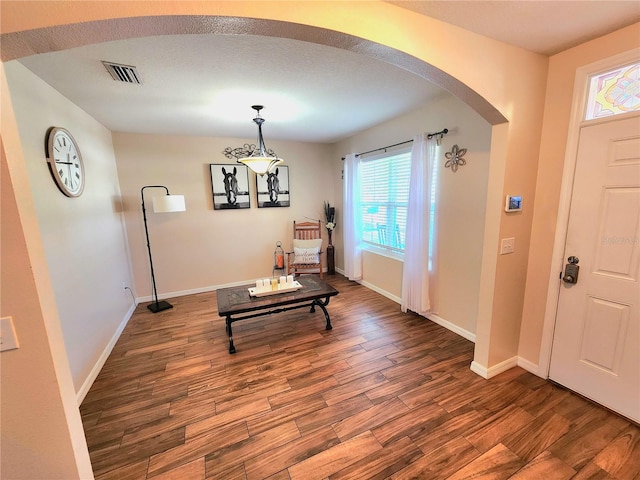 foyer entrance featuring arched walkways, visible vents, wood finished floors, and baseboards