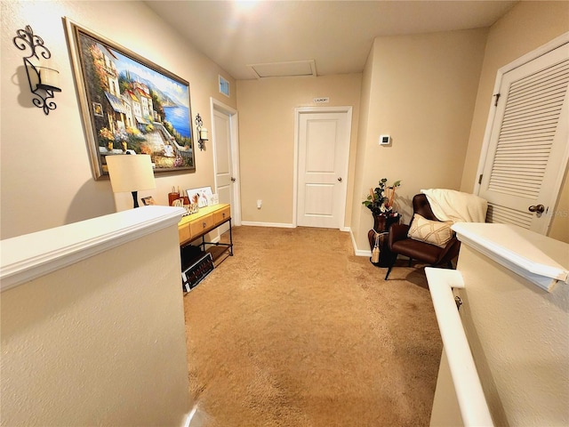 hallway with baseboards, attic access, and carpet floors