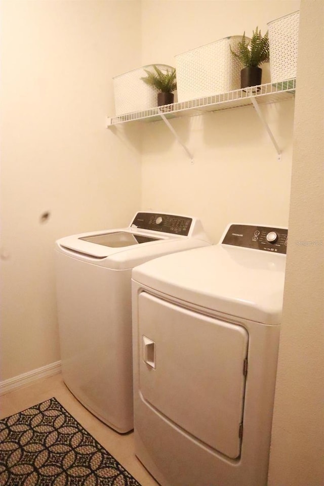 laundry room featuring light tile patterned floors, washing machine and clothes dryer, laundry area, and baseboards