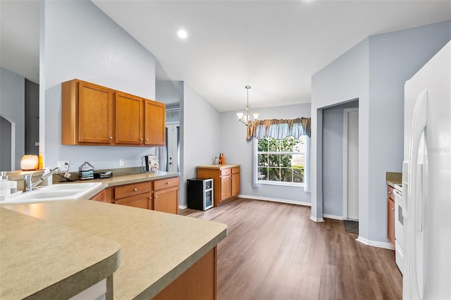 kitchen featuring sink, decorative light fixtures, kitchen peninsula, white appliances, and hardwood / wood-style floors