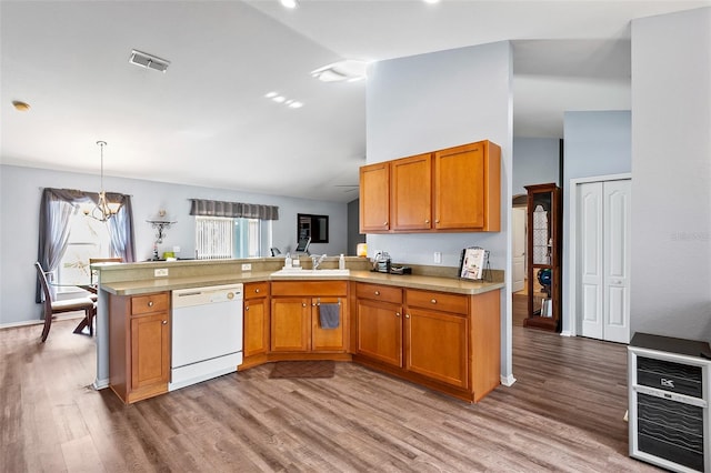 kitchen featuring pendant lighting, dishwasher, sink, and kitchen peninsula