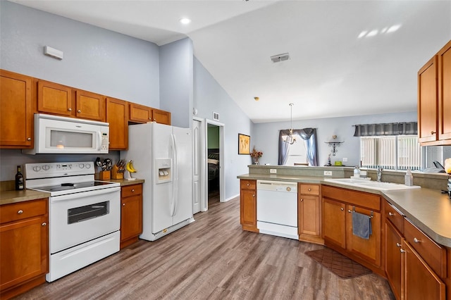 kitchen featuring sink, a chandelier, hanging light fixtures, light wood-type flooring, and white appliances