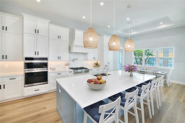 kitchen with white cabinetry, sink, an island with sink, and hanging light fixtures