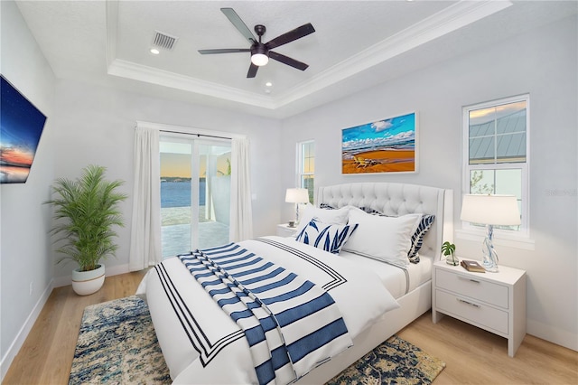 bedroom with a raised ceiling, ceiling fan, a water view, and access to outside