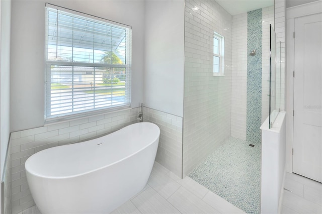 bathroom with tile patterned floors, tile walls, and shower with separate bathtub