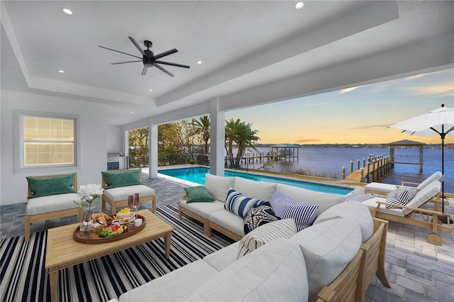 exterior space featuring ceiling fan, a water view, and a tray ceiling