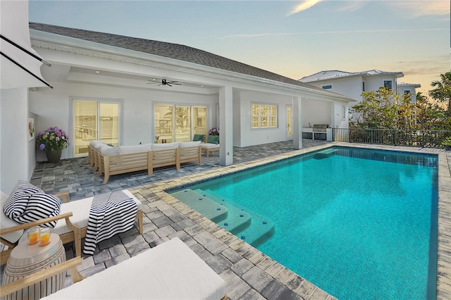 pool at dusk featuring ceiling fan, a patio area, and an outdoor hangout area