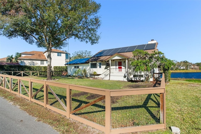 view of front of property with solar panels, a porch, a water view, and a front lawn