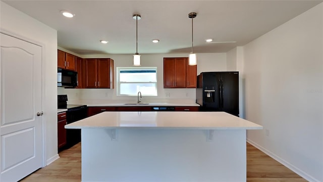 kitchen with a center island, sink, decorative light fixtures, a breakfast bar area, and black appliances