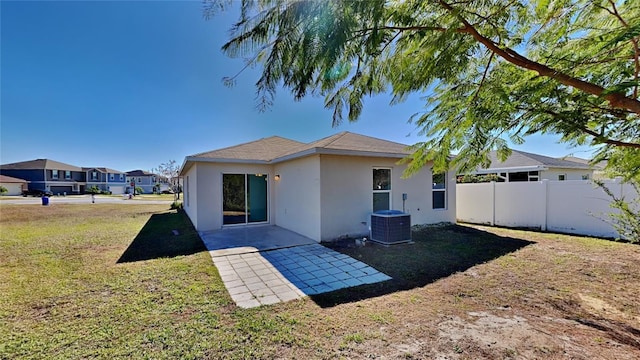 back of house featuring a yard, central AC unit, and a patio area