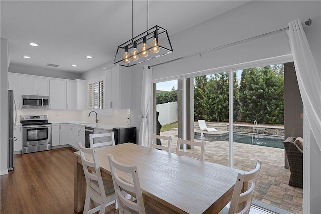 dining area with dark hardwood / wood-style floors, sink, and a chandelier