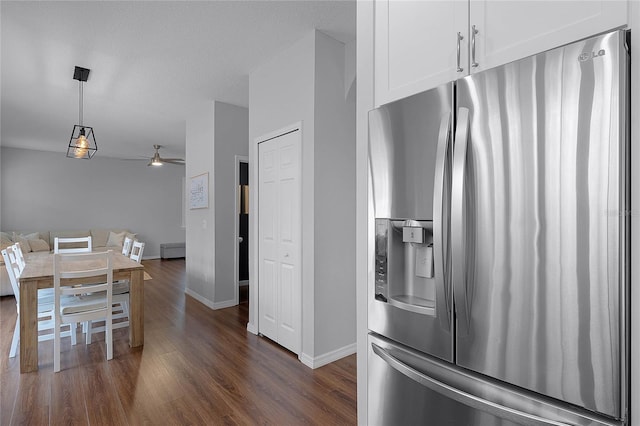 kitchen with stainless steel refrigerator with ice dispenser, dark hardwood / wood-style flooring, ceiling fan, white cabinets, and hanging light fixtures