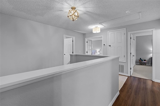 hallway with a textured ceiling and dark hardwood / wood-style flooring