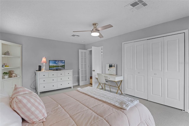 carpeted bedroom with ceiling fan, a closet, and a textured ceiling