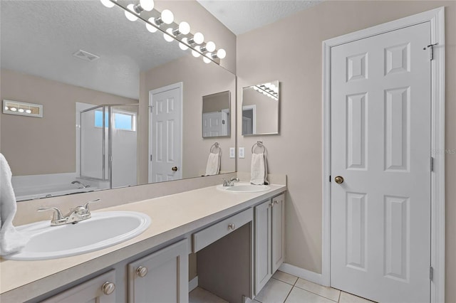 bathroom with vanity, a textured ceiling, tile patterned floors, and walk in shower