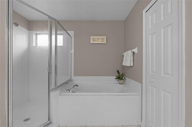 bathroom with a textured ceiling and shower with separate bathtub