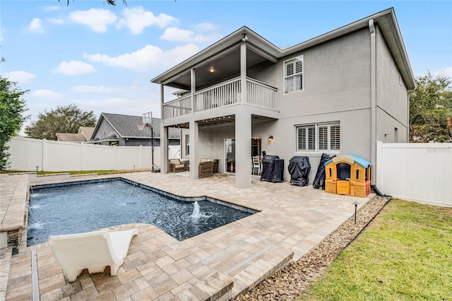 back of property with a fenced in pool, a patio area, pool water feature, and a balcony