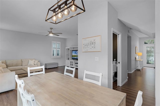 dining area featuring ceiling fan with notable chandelier and dark wood-type flooring