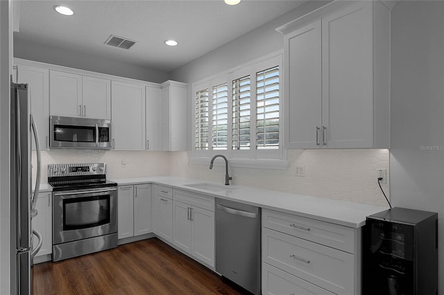 kitchen with dark hardwood / wood-style flooring, sink, white cabinetry, and stainless steel appliances