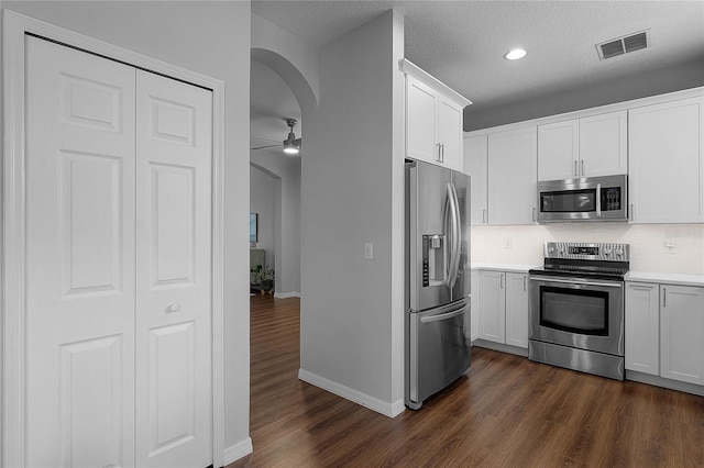 kitchen with ceiling fan, dark hardwood / wood-style flooring, white cabinets, and appliances with stainless steel finishes