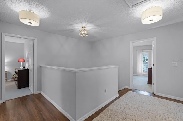 hall with a textured ceiling and dark wood-type flooring