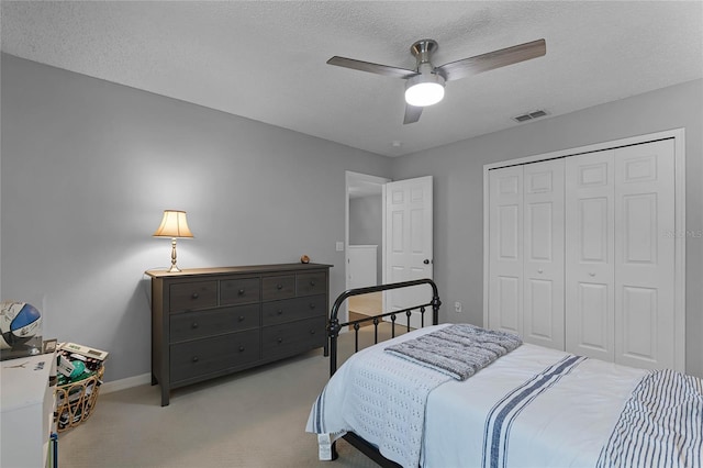 carpeted bedroom with a textured ceiling, a closet, and ceiling fan