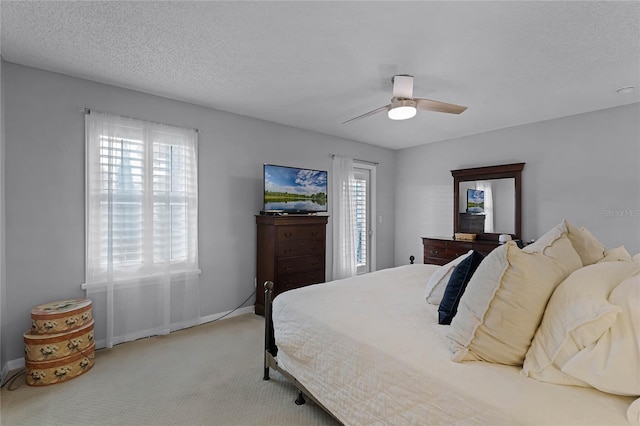 bedroom with multiple windows, ceiling fan, light colored carpet, and a textured ceiling