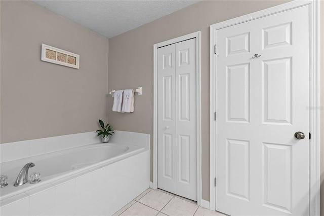 bathroom featuring tile patterned flooring, a textured ceiling, and tiled tub