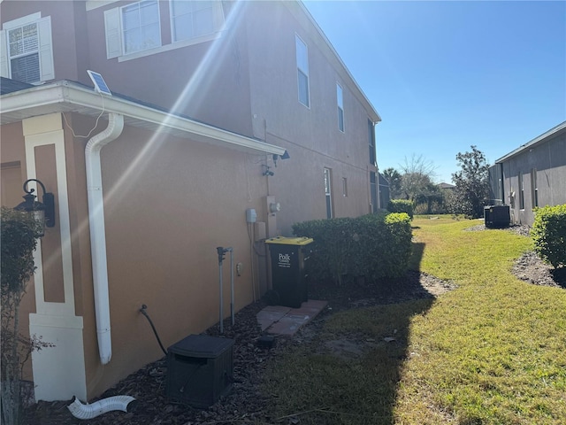 view of side of property featuring cooling unit and a lawn