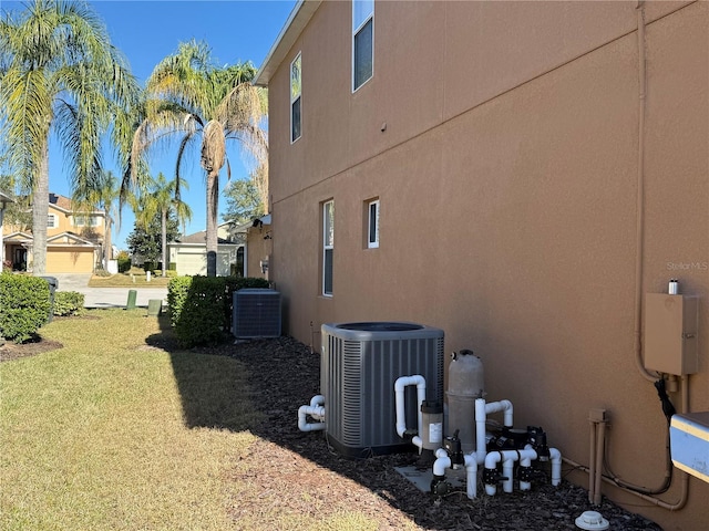 view of property exterior featuring central AC unit and a lawn