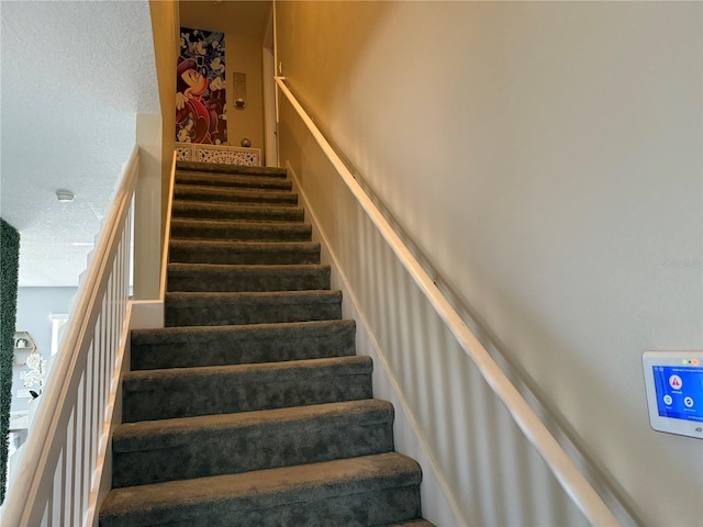 staircase featuring carpet and a textured ceiling