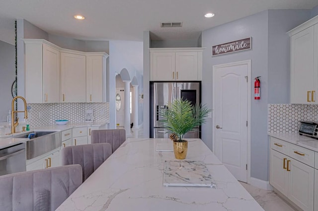 kitchen featuring white cabinetry, stainless steel appliances, backsplash, and sink