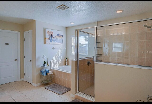 bathroom with a textured ceiling, tile patterned flooring, and separate shower and tub