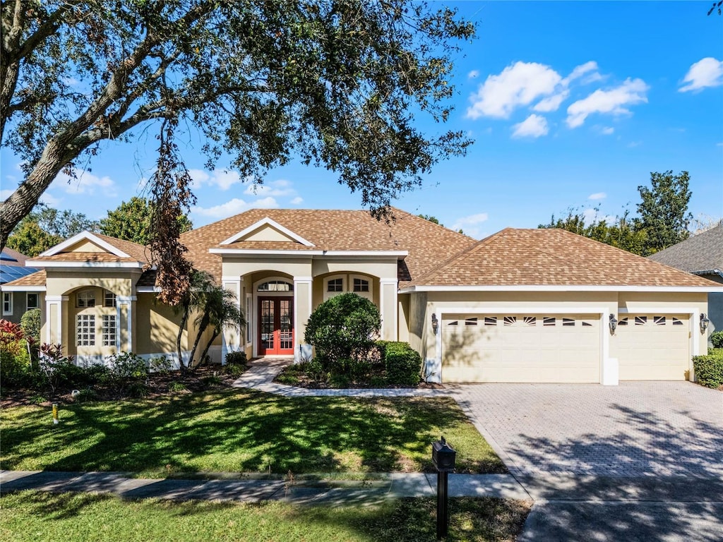 ranch-style home featuring french doors, a front yard, and a garage